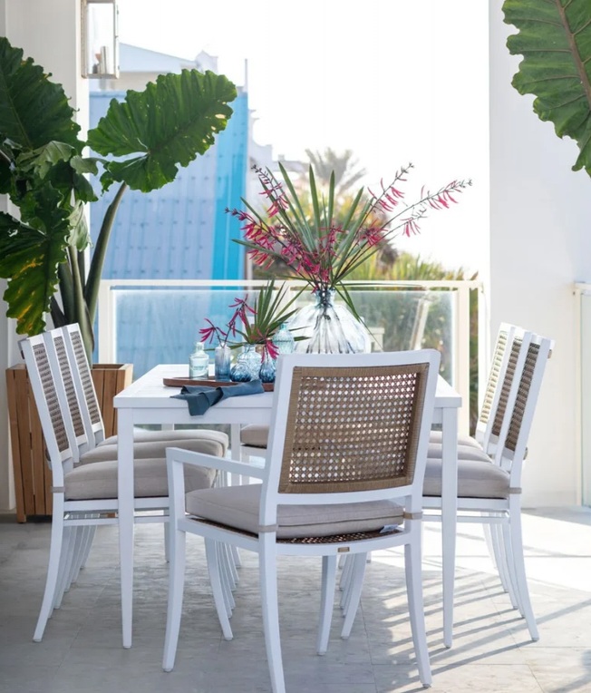 Bright terrace dining set surrounded by potted palms and lush garden planting