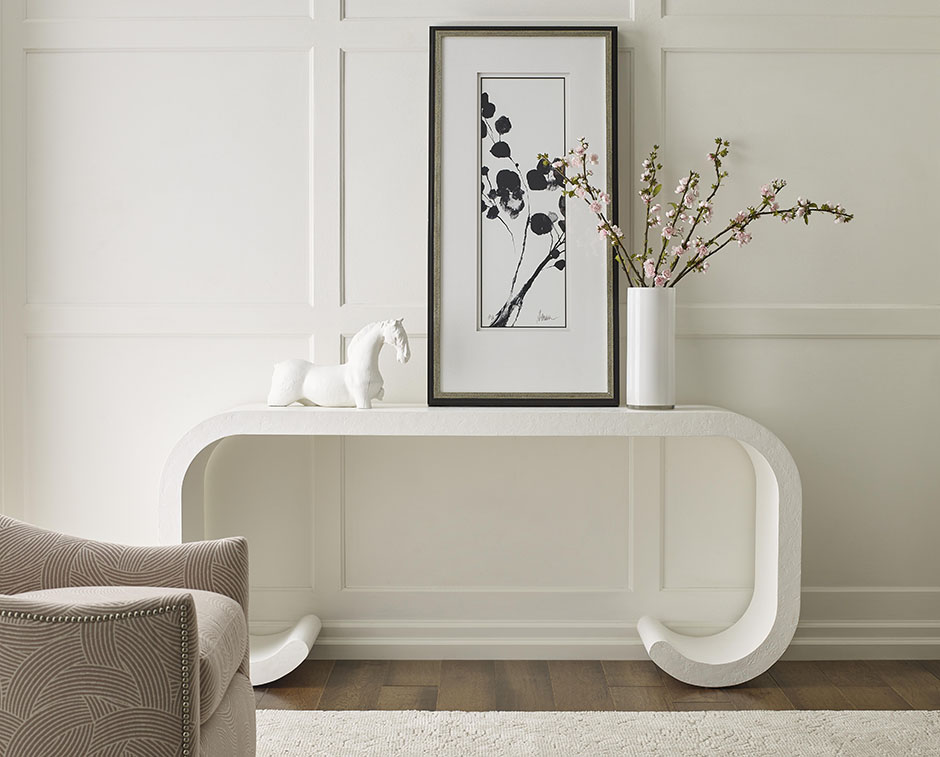 Console table vignette with framed art, sculptural branches, and layered found objects
